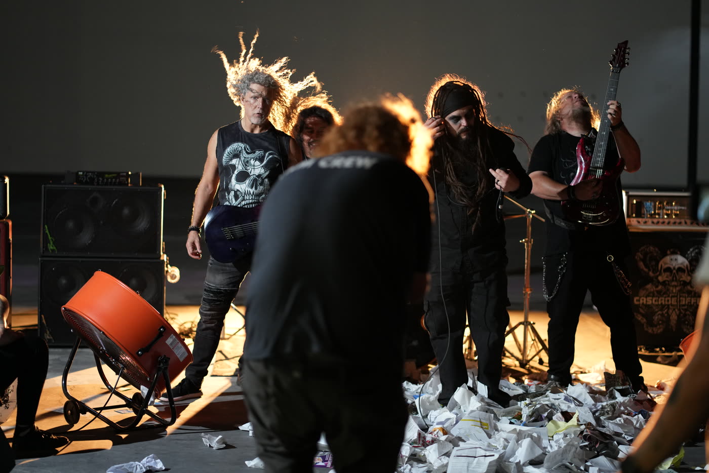 A band mid-take on a warehouse music video set, paper on the floor