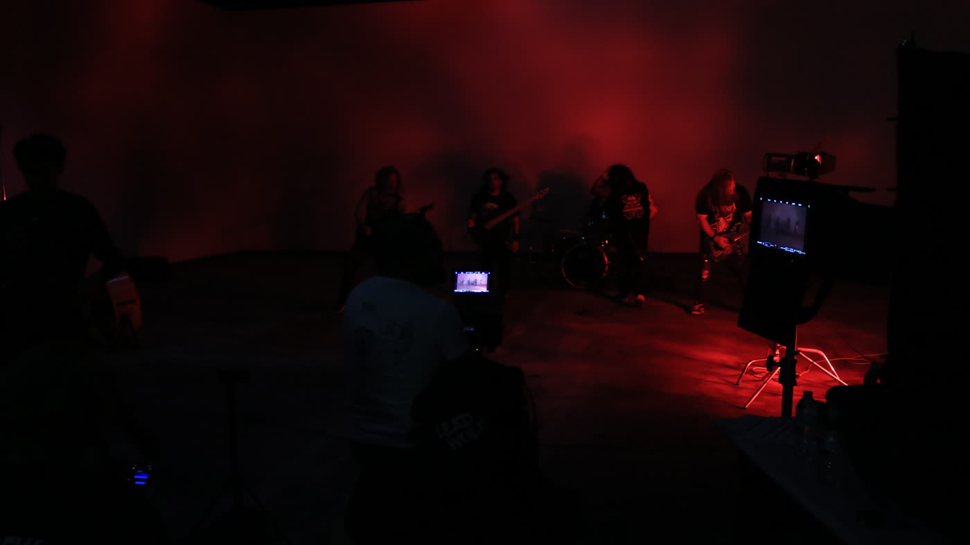 Drum kit under red light on a warehouse music video set