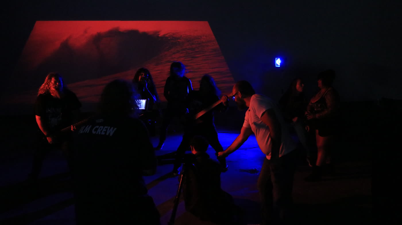 Crew filming the band against a red projection