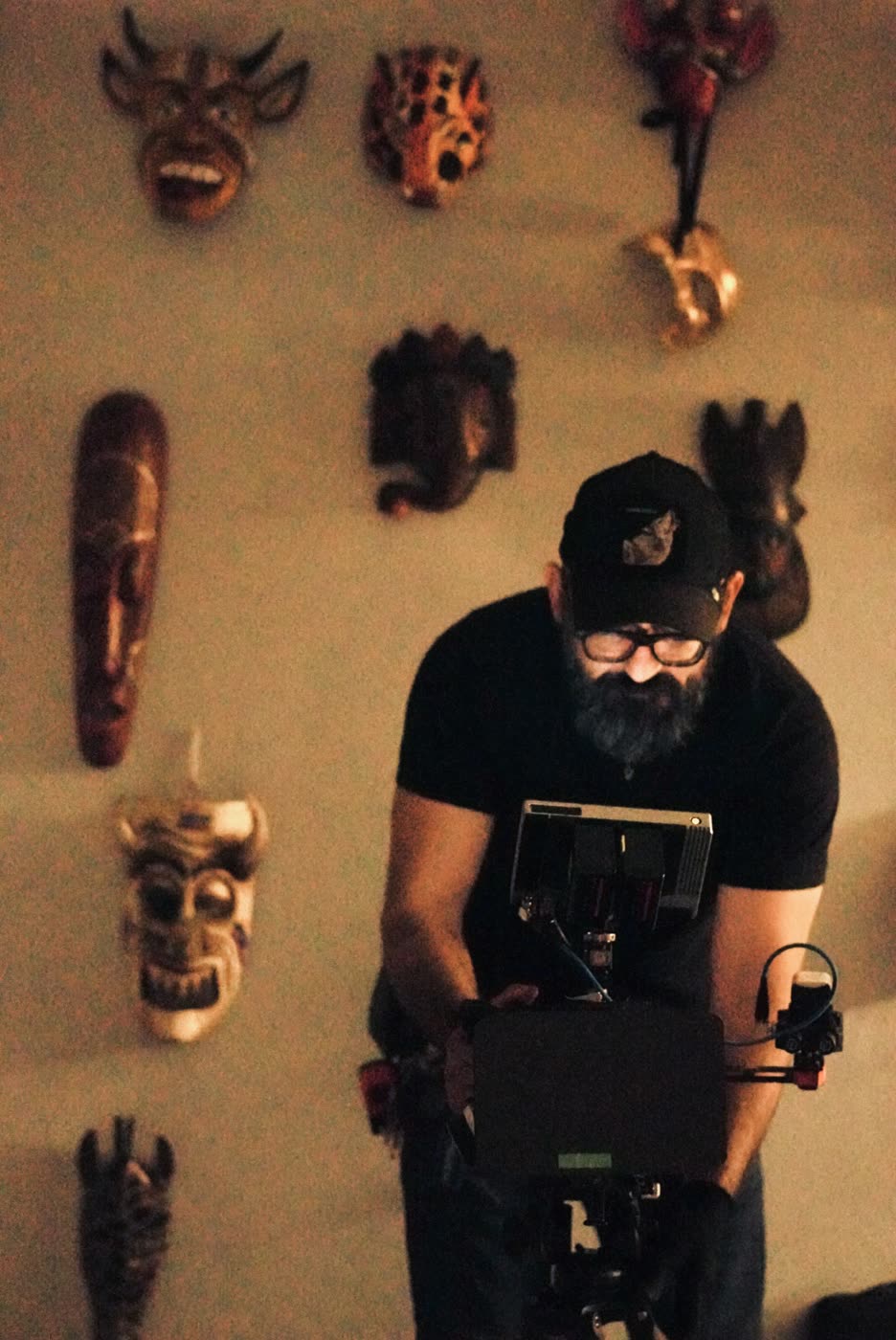 Oz Riveros framing a shot beneath a wall of masks