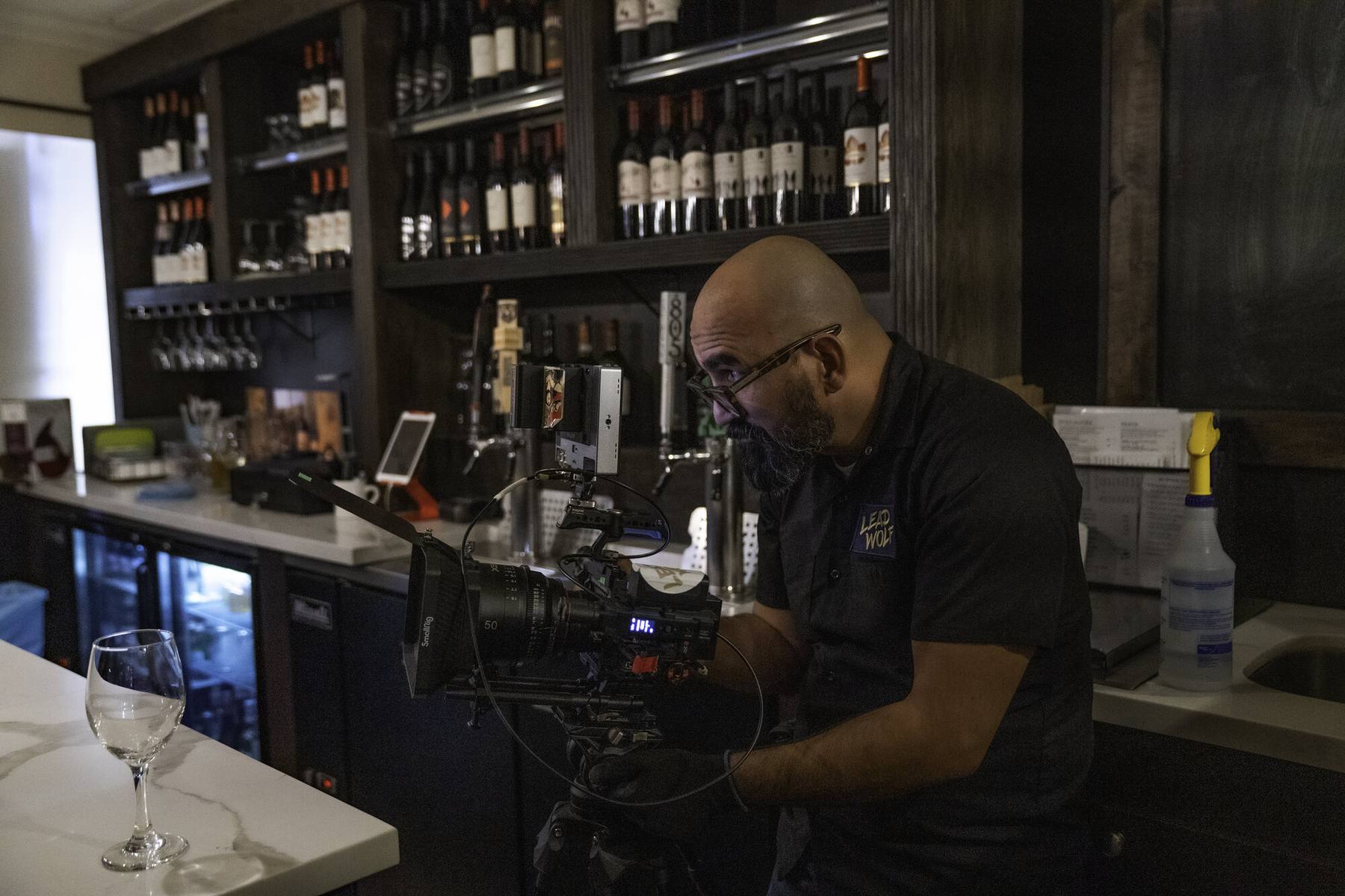 Oz Riveros operating the RED camera behind a restaurant bar on set